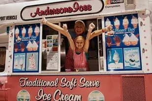 A young girl throwing her arms up with joy in the Andersons' Ices ice cream van window on her birthday